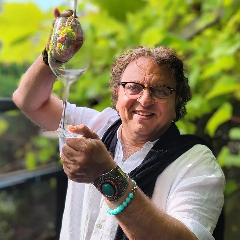 A picture of Chef Vikram Vij holding up a wine glass and grapes
