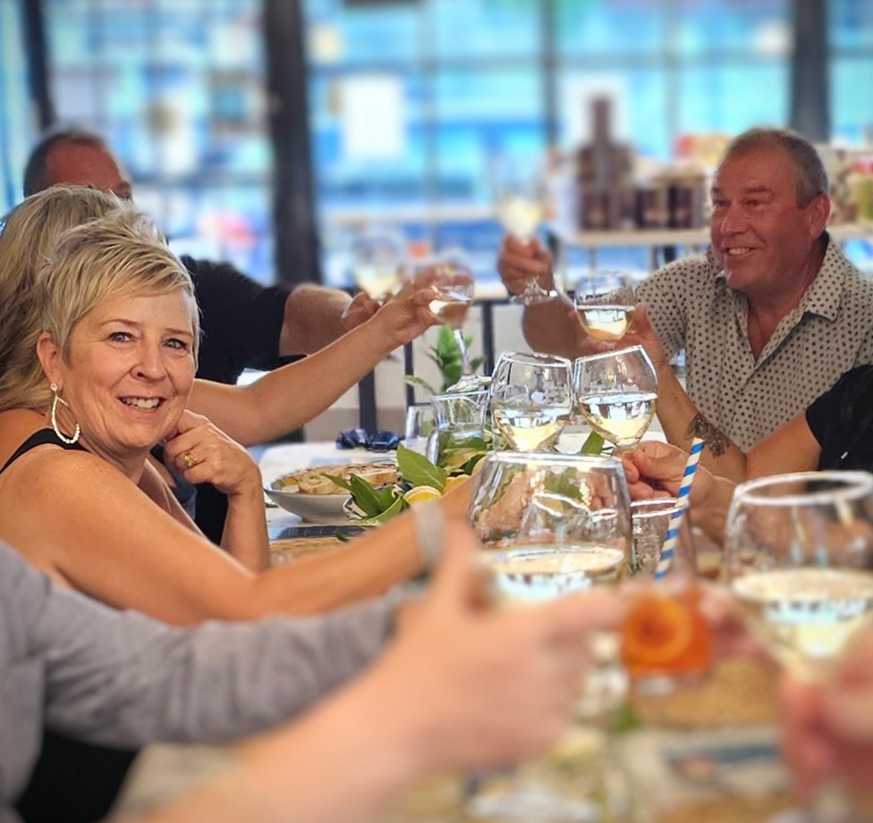 guests at the table raising a glass in cheers with the chef at capri