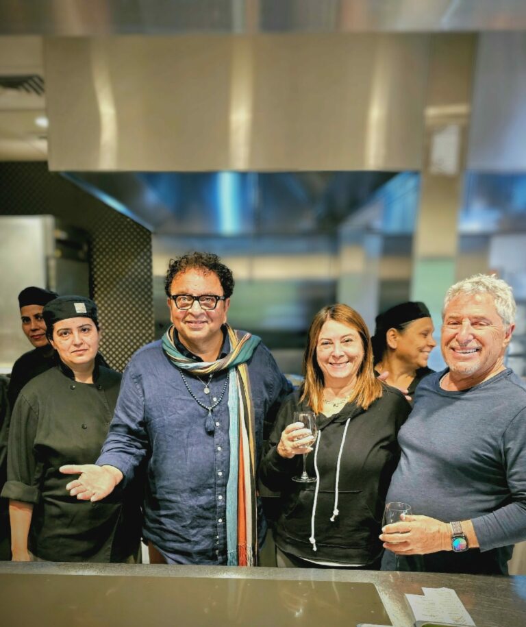 Chef Vikram Vij with guests in the kitchen enjoying a look behind the scenes at Vij's in Vancouver